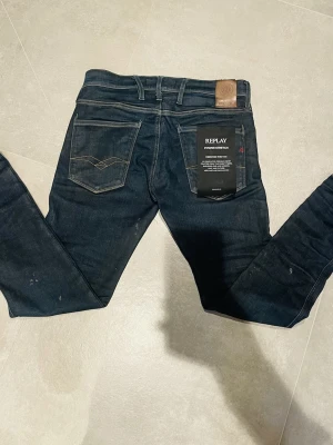Replay Anbass slimfit - Säljer ett par mörkblå Replay Anbass jeans med slim fit. Klassisk femficksmodell med snygga kontrastsömmar och power stretch för extra komfort. Märkespatch bak i midjan och diskreta slitningar för en cool look. Fläckarna tvättas såklart bort innan de fraktas