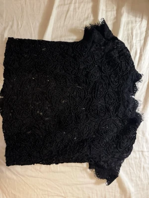 Svart spetsblus med dragkedja - Säljer en svart blus i spets med korta ärmar. Toppen går att ha på två sätt