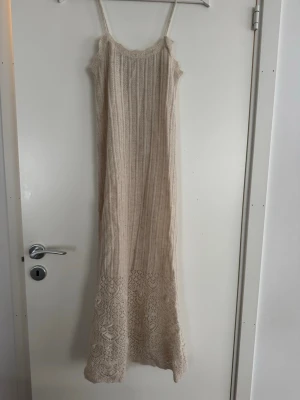 Beige lång stickad klänning med spets - Superfin beige långklänning med smala axelband och ribbad stickad struktur. 