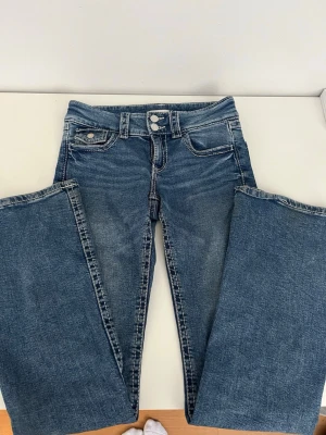 Blå jeans från Gina Tricot, stl 158 - Säljer ett par blå low-waist jeans med vita detaljer vid sömmarna som tyvärr passar inte längre. 