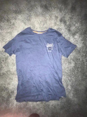 Blå Gant t-shirt med tryck - Snygg blå t-shirt från Gant med klassiskt tryck på bröstet och rund hals. Tillverkad i mjuk bomull som känns skön mot huden. Perfekt för dig som gillar enkel och stilren design med en sportig touch.