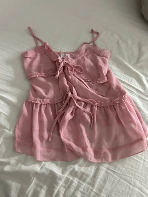 Rosa sommar linne - Ett luftigt linne med starkt material och snygga detaljer. Den perfekta sommar toppen för en sen sommar kväll vid bryggan. Den har aldrig varit andvänd då den var för stor på mig som är xxs så den är ganska stor och passar alla från storlek XS till S beroende på hur tait du vill ha den.