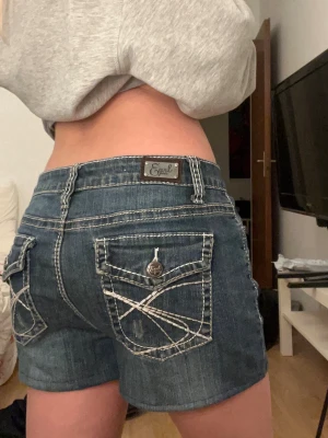 Mörkblå jeansshorts från Earl Jean - Säljer ett par mörkblå denimshorts från Earl Jean med kontrastsömmar och snygga bakfickor med lock och dekorativa knappar. Köpt second hand för två år sedan men har inte kommit till användning då de är lite för stora för mig. Finns inga tydliga defekter eller liknande. Skulle säga att dom passar s-m. Vid frågor är det bara att skriva 🤍