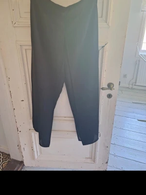 Svart croppad byxkjol - Säljer en svart croppad byxkjol med snyggt fall och lätt utsvängda ben. Byxorna har en enkel och stilren design, perfekta till en trendig look. Materialet känns lätt och luftigt. Djur finns i hemmet.