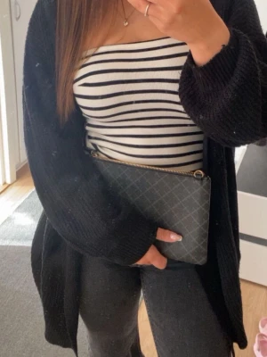 Randig tubtopp  - Säljer en vit och svart randig tubtopp. Toppen är ärmlös och har en tight passform som sitter snyggt på kroppen. Perfekt att styla med jeans eller kjol för en enkel och trendig look.