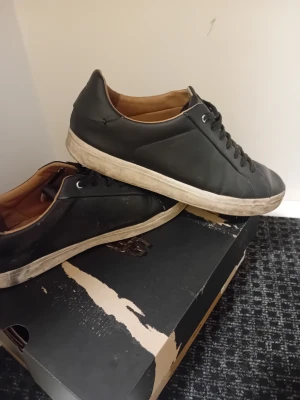 Svarta sneakers från Race Marine i skinn med snörning - Svarta sneakers med klassisk låg profil och rund tå. Skorna har ovandel i skinn, vita platta gummisulor och svarta snören. Insidan är beige och ger en snygg kontrast mot det svarta yttermaterialet. Perfekt för dig som gillar stilrena och enkla sneakers.