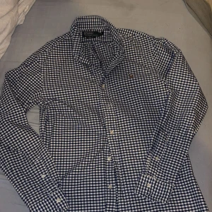 Blårutig skjorta från Polo Ralph Lauren - Snygg blårutig skjorta från Polo Ralph Lauren i slim fit. Skjortan har klassisk krage, långa ärmar och knappar framtill. Materialet är mjuk bomull och på bröstet finns den ikoniska broderade Polo-loggan. Perfekt för dig som gillar stilrena och tidlösa plagg.