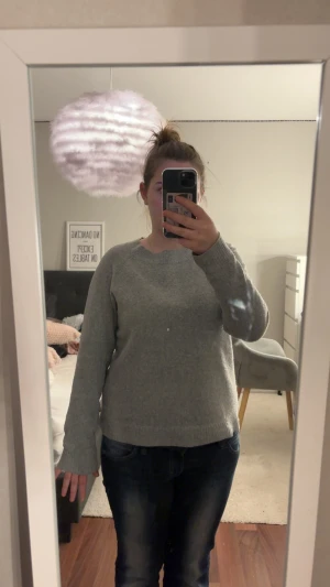 Grå stickad tröja från Vero Moda - Mysig grå stickad tröja från Vero Moda i storlek S. Tröjan har rund halsringning, långa ärmar och ribbade muddar vid ärmslut och nederkant. Perfekt för kyliga dagar och enkel att matcha med jeans eller kjol.