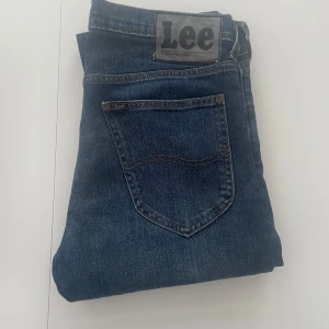 Lee jeans mörkblå - Mörkblå Lee  jeans med klassisk femficksdesign och raka ben. Snygg tvätt med lätt slitning och Lee-logga på bakfickan. Tillverkade i bomull med en skön passform som funkar till det mesta.