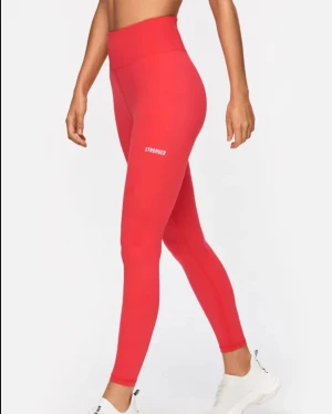Röda leggings från Stronger XS - Snygga röda leggings från Stronger i storlek XS. De har hög midja och är tillverkade i ett stretchigt och mjukt syntetmaterial som sitter tight och bekvämt. Perfekta för träning och har en enkel design med logga på benet. Aldrig använt, därav nytt skick. Ord pris 799kr