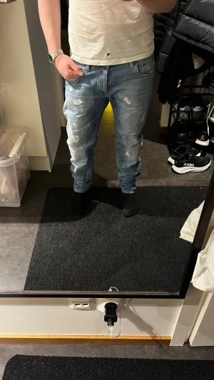 G-Star ljusblå jeans med slitningar - Säljer ett par ljusblå jeans från G-Star med snygga slitningar och tvättade detaljer. Modellen har raka ben och klassisk femficksdesign. Jeansen är tillverkade i mjukt bomullsmaterial och har normal passform. Perfekt för dig som gillar en avslappnad streetstil.