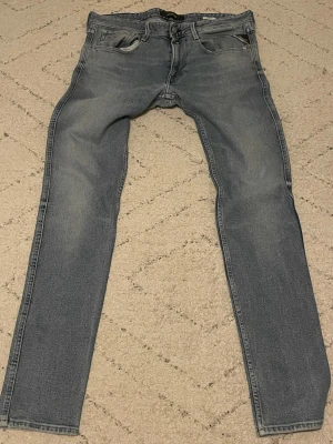 Replay Anbass ljusgrå jeans, stl 34 - Säljer ett par Replay Anbass jeans i ljusblå tvätt med klassisk femficksdesign och snyggt broderad bakficka. Jeansen har rak passform och normal midja, tillverkade i mjukt jeanstyg för skön känsla. Perfekt för dig som gillar stilrena och moderna jeans. Helt oanvända och i 10/10 skick. Pris går att diskuteras!!