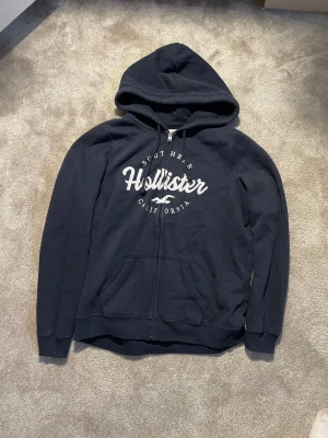 Hollister Hoodie  - Hej! Säljer nu denna väldigt snygga och eftertraktade Hollister Hoodie! Tröjan är slutsåld överallt och går inte att få tag på… Tröjan är perfekt nu till vintern. Storlek L Säljs för: 349