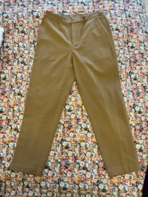 Beige kostymbyxor i ullmix - Snygga beige kostymbyxor med diskret fiskbensmönster. Byxorna har hög midja, raka ben och bälteshällor. Tillverkade i en mjuk ullmix som ger en klassisk och clean look. Perfekta till en stilren outfit.