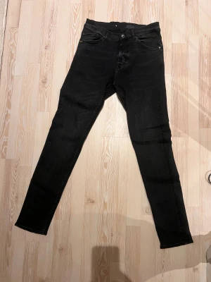 Svarta skinny jeans från tiger of sweden  - Svarta jeans från tiger of sweden med klassisk femficksdesign och smal passform. Jeansen har normal midja och är tillverkade i stretchigt denimtyg för extra komfort. Perfekta för dig som gillar en stilren och enkel look.