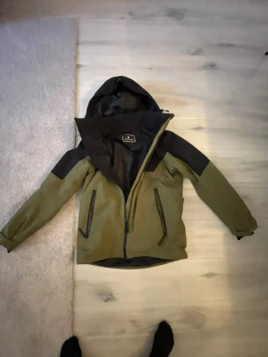 Grön vindjacka från Cross Sportswear - En skön grön svart jacka, det är en skidjacka som har använts 1 helg och inget mera.