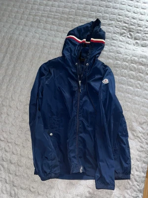 Moncler Regnjacka - Säljer min Moncler regnjacka då den ej passar mig. Knappt använd och i riktigt bra skick. Storleken är 4 vilket motsvarar XL i vanlig storlek. 