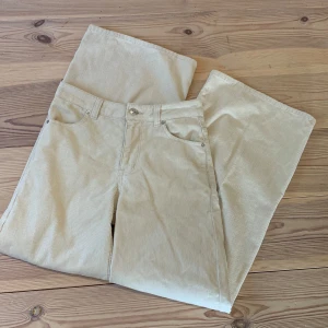 Beiga manchesterbyxor wide fit - Säljer ett par snygga beiga manchesterbyxor med breda ben och klassisk femficksdesign. Byxorna har hög midja och är tillverkade i mjukt manchestertyg som ger en chill och trendig vibe. Perfekta för dig som gillar loose och relaxed stil.