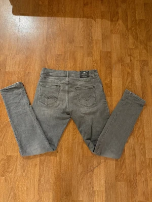 Replay grå jeans slim fit Wallys - Snygga grå jeans från Replay med slim fit och klassisk femficksdesign. Jeansen har raka ben, diskreta slitningar och svarta Replay-detaljer vid fickan. Perfekt för dig som gillar en stilren och modern look. W29 L32