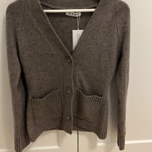 Brun kofta från Wera med fickor - Mysig brun kofta från Wera i storlek XS. Koftan har v-ringning, tre knappar framtill och två ribbstickade fickor. Materialet är stickat och känns skönt mot huden. Perfekt att slänga på sig när det är lite kyligt ute. Helt oanvänd och splitter ny , passade it mig så drf säljer jag 🥹