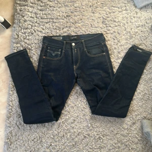 Replay mörkblå jeansbyxor 29/32 - Säljer ett par mörkblå jeans från Replay med klassisk femficksdesign och snygga kontrastsömmar. Byxorna har raka ben och coola broderade detaljer på bakfickorna. Perfekt passform och stilren look för dig som gillar jeans med attityd. Moddelen är anbass. De är lite skrynkliga men de fixas när jag skickar varan.