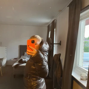 Svart dunjacka från Jott med huva - Säljer en svart dunjacka från Jott med huva och dragkedja framtill. Jackan är puffig och har en clean look, perfekt när du vill hålla dig varm. Insidan har en cool serietidningsetikett och Jott-logga. Passformen är normal och jackan är långärmad. Inga hål har använd ett par gånger men har ingen använd av den.