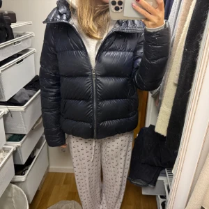 Mörkblå Colmar pufferjacka med huva - Säljer en snygg mörkblå deluxe down jacket från collage. Orginalpris ca 7000kr. Använd men i mycket fint skick. Storlek 46 vilket motsvarar 36/S i europeiska storlekar. 