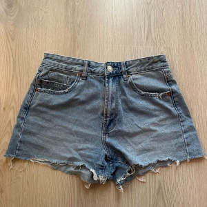 Blå denimshorts från Stradivarius - Säljer ett par blå denimshorts från Stradivar.  Perfekta för sommaren och lätta att matcha med allt. Jeansmaterialet är mjukt och bekvämt.