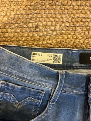 Replay Anbass ljusblå slim jeans 32 - Säljer ett par Replay Anbass Hyperflex jeans i ljusblå tvätt. Modellen är slim fit med klassisk femficksdesign och snygga detaljer på bakfickorna. Jeansen är tillverkade i stretchigt jeansmaterial för extra komfort och har normal midja.