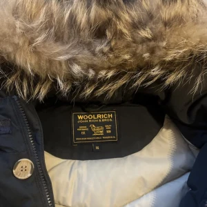 Woolrich vinterjacka  - Säljer min Woolrich Arctic Parka i mörkblå färg, storlek 16 (motsvarar ca XS/S) men är stor i storleken så passar även större. Jackan är i mycket bra skick – sparsamt använd, inga fläckar eller skador! Det är verkligen en varm vinterjacka + pälsen är avtagbar.  Nypris ca 9 500 kr. Pris: 1 299 kr(eller bud)