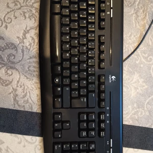 Logitech USB Tangentbord - Logitech tangentbord med USB-anslutning, klassisk svart design och fullstort layout. Tangenterna är tydliga och tangentbordet är i nytt skick utan synligt slitage. Perfekt för både arbete och spel. Plug & play med Windows och andra operativsystem.