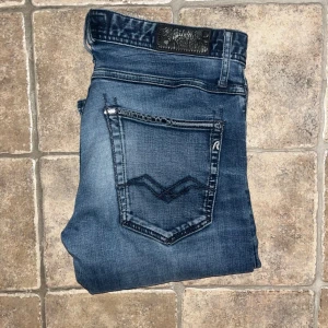 Replay jeans  - Snygga Replay jeans i mörkblå tvätt med slitningar och klassiska detaljer på bakfickorna. Modellen är skinny och stretchigt jeanstyg som sitter tajt längs benen. Perfekt passform för dig som gillar smal siluett. Midja 41cm, längd 108cm. JAG SKICKAR EJ FLER BILDER NÄR JAG BÄR JEANSEN! för storleksguide hänvisar jag till måtten och för bättre inblick i passformen rekommenderar jag att googla på modellnamnet. Jeansen kan vara uppsydda utan att jag noterat det så kolla måtten noggrant :) s4