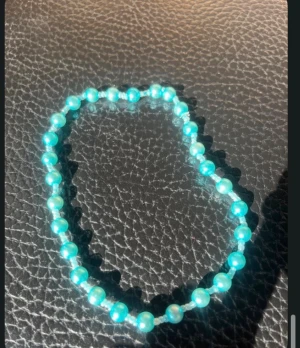 Turkost pärlarmband eller halsband  med glans - Ett snyggt armband eller halsband med turkosa pärlor som skimrar i ljuset. Pärlorna är runda och sitter på en elastisk tråd, vilket gör det enkelt att ta på och av. Perfekt accessoar för att ge din outfit lite extra färg och stil.