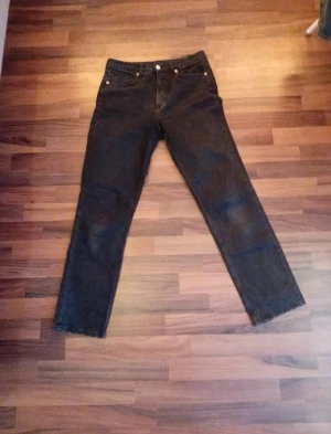 Svarta jeans straight fit - Klassiska svarta jeans med rak passform och fickor. Jeansen har knappgylf och är tillverkade i denimtyg. Perfekta för dig som gillar tidlös stil och vill ha ett par jeans som funkar till allt.