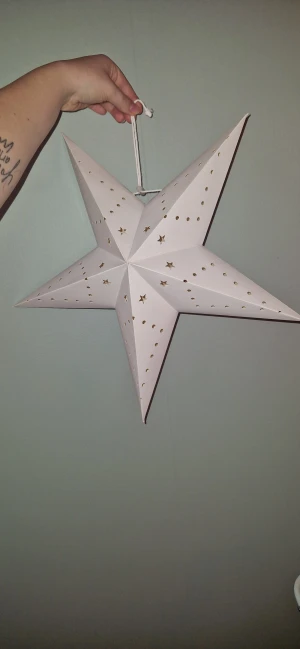 Vit adventsstjärna med hålmönster - Stilren vit adventsstjärna i papper med dekorativa hål och stjärnmönster. Perfekt för fönsterupphängning. Fästes med medföljande snöre. Snöret har gått upp-men kan knytas ihop, men i gott skick och redo att användas för mysig belysning.