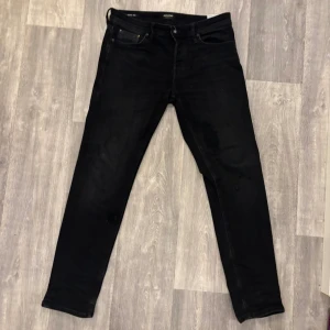 Svarta Jack and Jones jeans - Svarta jeans från Jack and Jones i storlek 31/32. Modellen heter tapered Mike som har en passform som smalnar av nedtill och klassisk femficksdesign. Jeansen är tillverkade i ett mjukt jeansmaterial och har en stilren look som funkar till sneakers eller boots. Köpte i jack and Jones affär för ca 900 kr, mitt pris går att diskuteras.