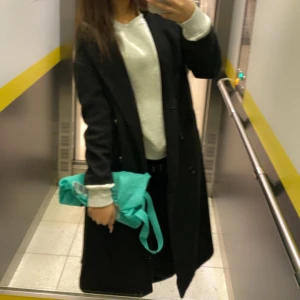 Svart lång kappa med knappar - Säljer en svart, stilren och lång kappa med knappar framtill. Jackan har en rak passform och är perfekt för dig som gillar en clean och klassisk look. Passar dig som vill ha en enkel men snygg jacka till höst och vinter. Passar  xs-s