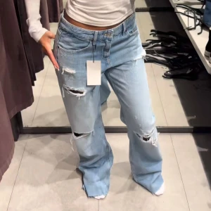 Ljusblå ripped jeans med wide fit - Säljer ett par ljusblå jeans med slitna detaljer och hål på benen. Modellen har en bred, loose passform och är tillverkad i klassiskt denimtyg. Perfekt för dig som gillar en avslappnad och trendig stil med extra edge. Passar inte mig så bra men super snygga och trendiga 💕💕💕