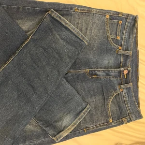 Blåa Diesel jeans  - Snygga blå jeans från Diesel med klassisk femficksdesign och raka ben. Jeansen har kontrastsömmar, läderpatch med Diesel-logga bak och subtila slitningar framtill. Passformen är normal och materialet är robust denim. Perfekt för dig som gillar stilrena och tidlösa jeans.