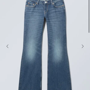 Weekday Nova Low Slim Bootcut Jeans - Snygga bootcut jeans från Weekday i modellen Nova Low Slim Bootcut. De är blå med ljusare tvättade partier och har klassisk femficksdesign. Jeansen har låg midja och är tillverkade i jeansmaterial med dragkedja och knapp framtill.