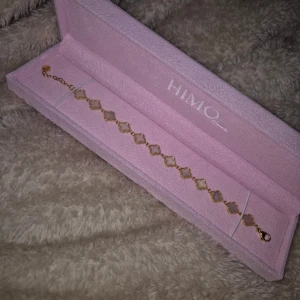 HIMO armband - Säljer ett nytt armband från HIMO. Vändbar (kolla bilder) har guldfärgade länkar med fyrklöverformade detaljer. Har vita inslag i varje länk, medan det andra sidan har glittriga detaljer. 