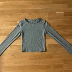 Ljusgrön långärmad topp - Säljer en stilren ljusgrön långärmad topp med rund hals. Toppen är croppad och har en enkel, clean look utan mönster eller detaljer. Materialet känns mjukt och stretchigt, troligen bomull eller polyester. Perfekt att matcha med jeans eller kjol för en chill vibe.