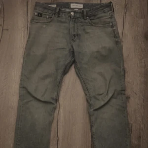 Grå Calvin Klein jeans - Säljer ett par grå jeans från Calvin Klein. Jeansen har fem fickor, klassisk knapp och dragkedja framtill samt bälteshällor. Materialet är jeans med en tvättad look och smal passform som sitter snyggt på benen. Dom kostar 1399 nya från butik.