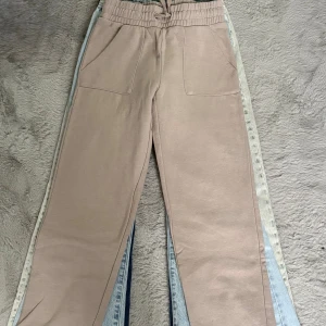 Beige mjukisbyxor med snörning - Säljer ett par beige mjukisbyxor med bred resår och snörning i midjan. Byxorna har två stora fickor fram och är tillverkade i mjukt material som ger en chill och avslappnad vibe. Perfekta för att hänga hemma eller dra till gymmet.