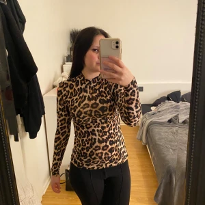 Leopardmönstrad långärmad topp Amisu XS - Säljer en slim långärmad topp från Amisu i storlek XS med leopardmönster i bruna och svarta toner. Toppen har en hög hals och är figurnära, perfekt för dig som gillar djurmönster och vill sticka ut. Materialet är mjukt och stretchigt, troligen polyester. Den är stretchiga!