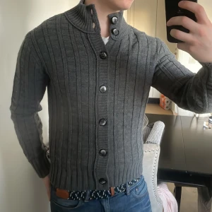 Grå stickad cardigan - Riktigt fin grå stickad cardigan, perfekt till kallare väder. Modellen är 180cm, 73kg. Priset går såklart att diskutera!