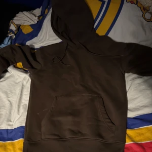 Mörkbrun hoodie med huva och ficka - Säljer en enkel och stilren mörkbrun hoodie med stor magficka och huva med snörning. Perfekt för chill dagar och passar till det mesta. Mjuk och skön känsla, långärmad modell med klassisk passform.