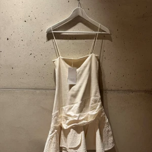 Vit kort klänning från Zara - Säljer en vit kort klänning från Zara med smala axelband. Klänningen har en cool volangdetalj nedtill och är tillverkad i mjukt material med en mix av texturer. Superfin till studenten eller midsommar! Har aldrig använt!😸