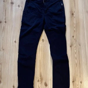 Marinblå chinos från Win Win, L - Snygga marinblå chinos från Win Win i storlek L. Byxorna har klassisk rak passform, sidofickor fram och diskreta bakfickor. Tillverkade i mjukt bomullsmaterial som är skönt mot huden. Perfekt för dig som gillar stilrena och bekväma byxor.