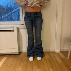 Levi's Low Flare jeans blå - Snygga blå jeans från Levi's med låg midja och bootcut/flare-ben. Modellen är Low Slim Flare med klassiska fem fickor, slitningar och kontrastsömmar. Innerbensmått: 80 cm  Ytterbensmått: 98 cm  Midjemått tvärs över: 36 cm  Lårmått: 20 cm  Grenmått: 19 cm                                                                    (35) 